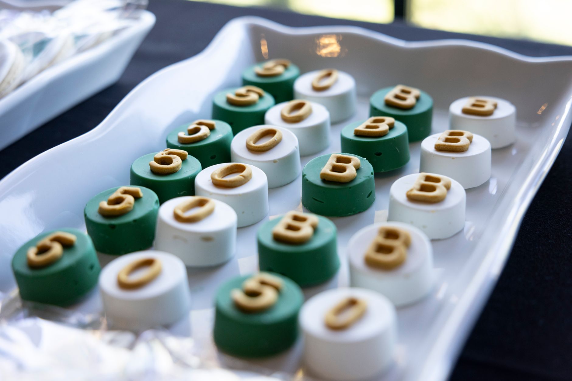 Tray of round green and white candies with personalized gold letterings for event or celebration.
